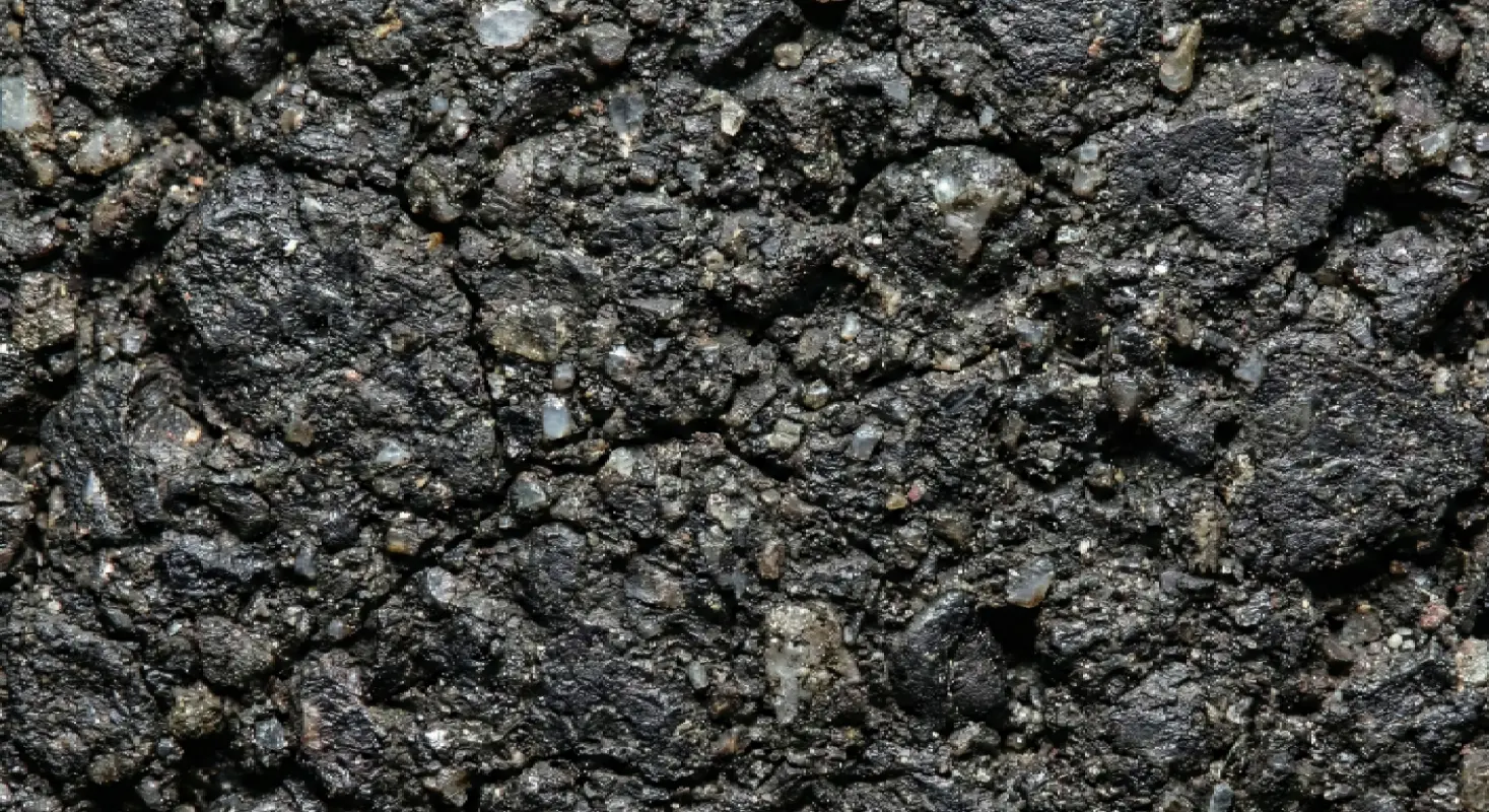 Close up macro photography of oxidized gray asphalt versus black sealcoated asphalt surface showing texture.