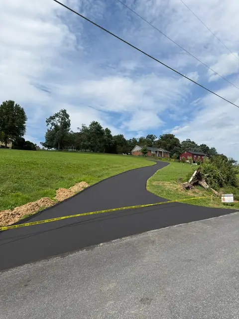 Sealcoated driveway apron at the road, taped off while it cures