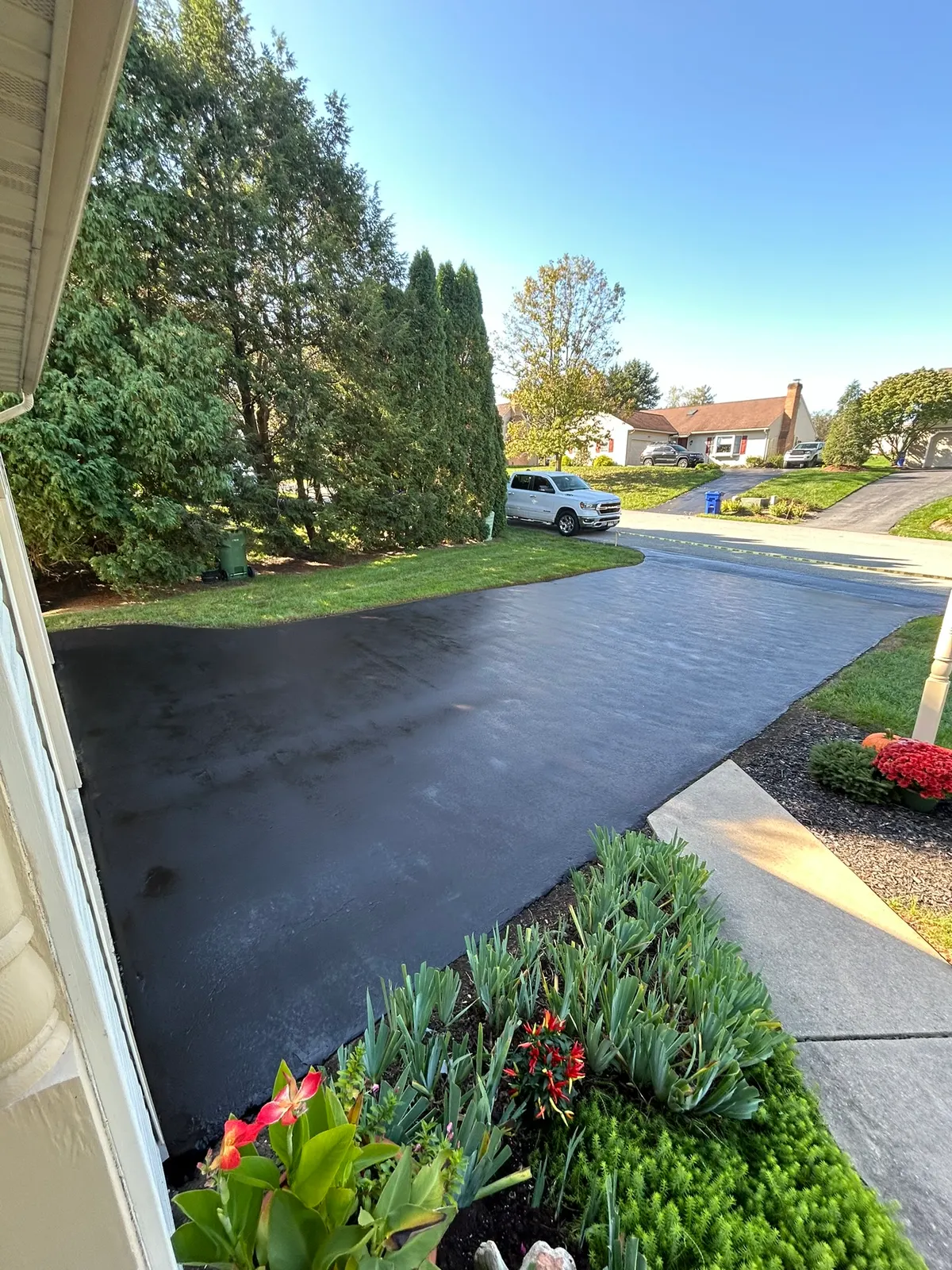 Freshly sealcoated driveway running alongside flower beds