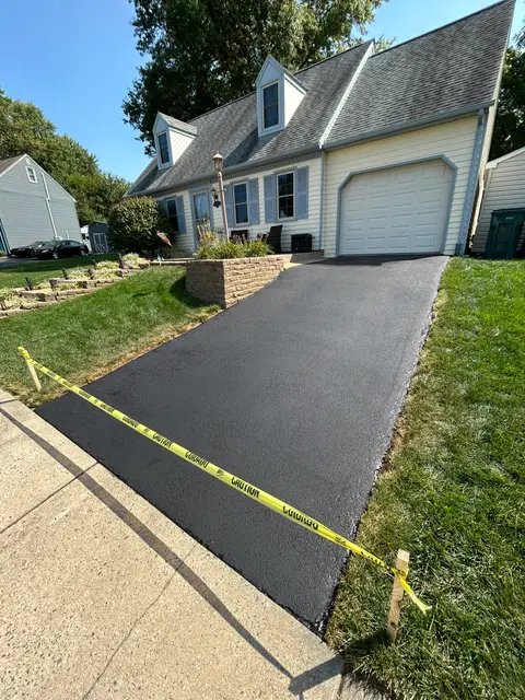 Sloped driveway sealcoated in front of a Cape Cod style home