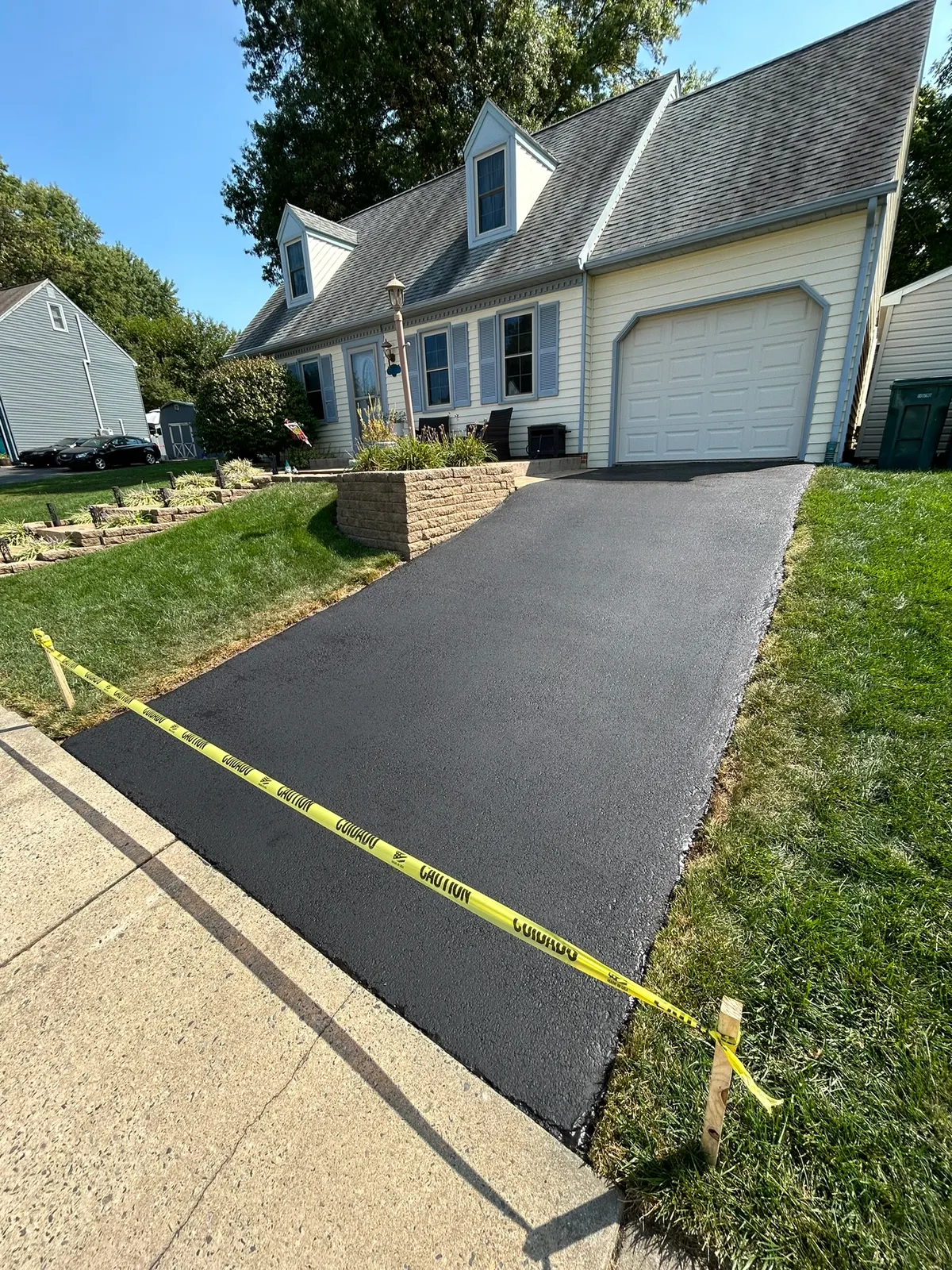 Sloped driveway sealcoated in front of a Cape Cod style home