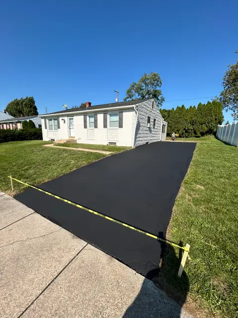 Narrow driveway at a small home sealcoated in even black