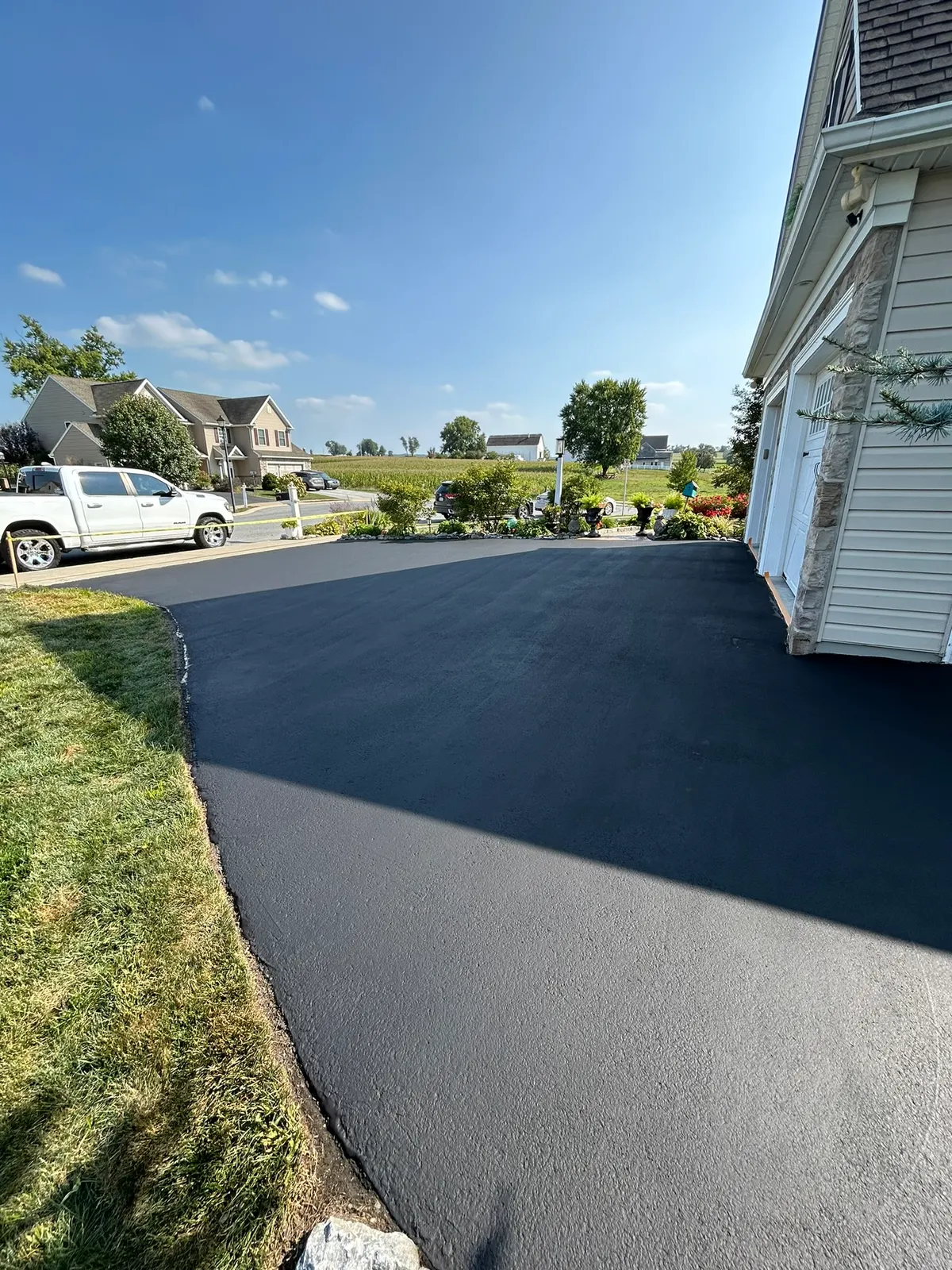 Wide sealcoated driveway apron in front of a two-car garage