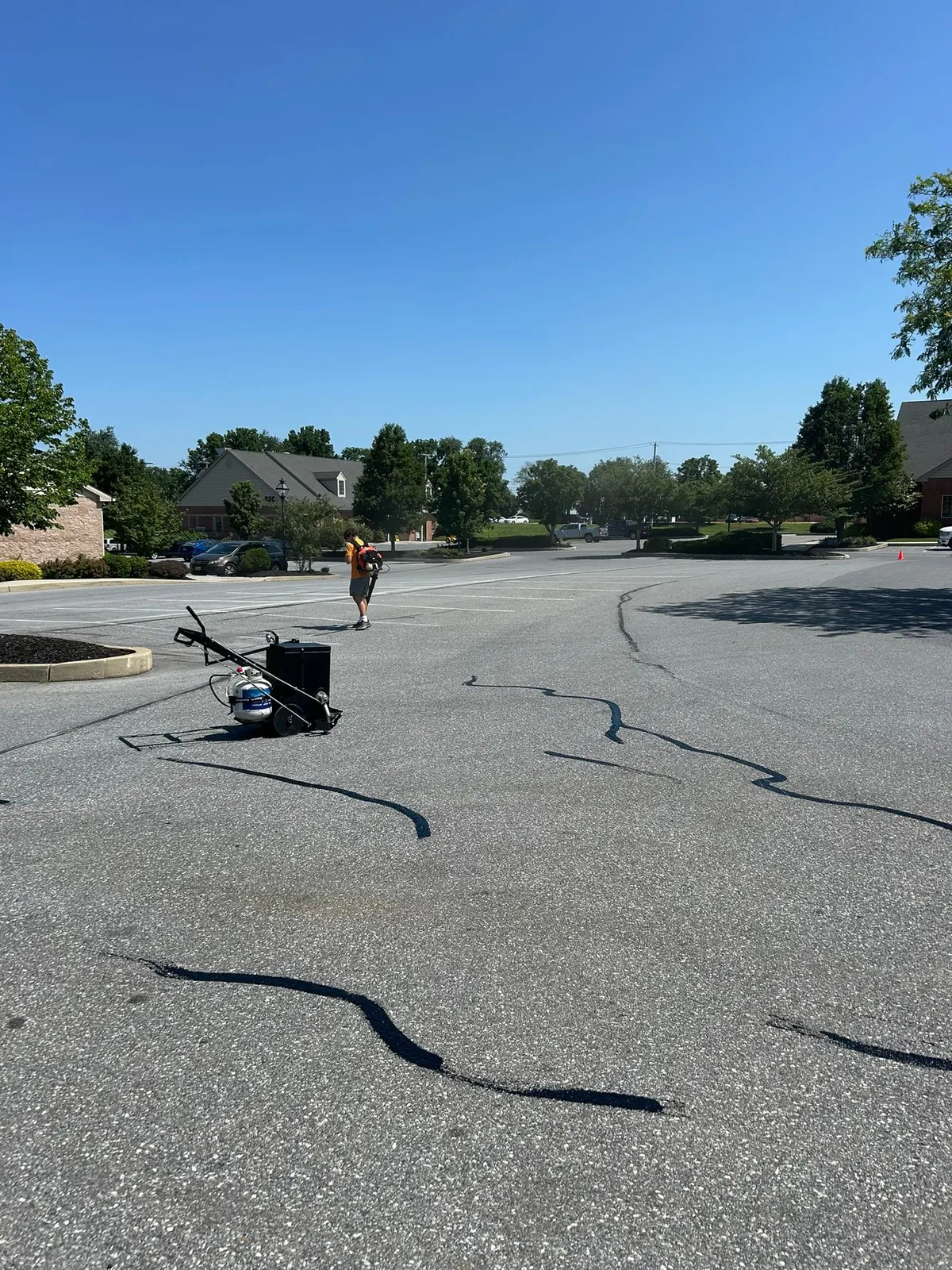 Crack sealing equipment and freshly filled cracks across a parking lot