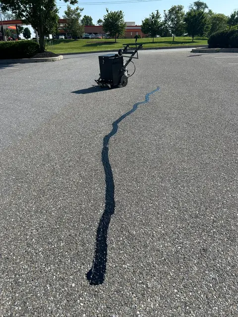 Hot pour crack sealer filling a long crack across a parking lot