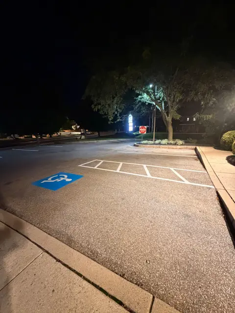 Blue ADA stall with white access aisle hatching painted at night beside a curb