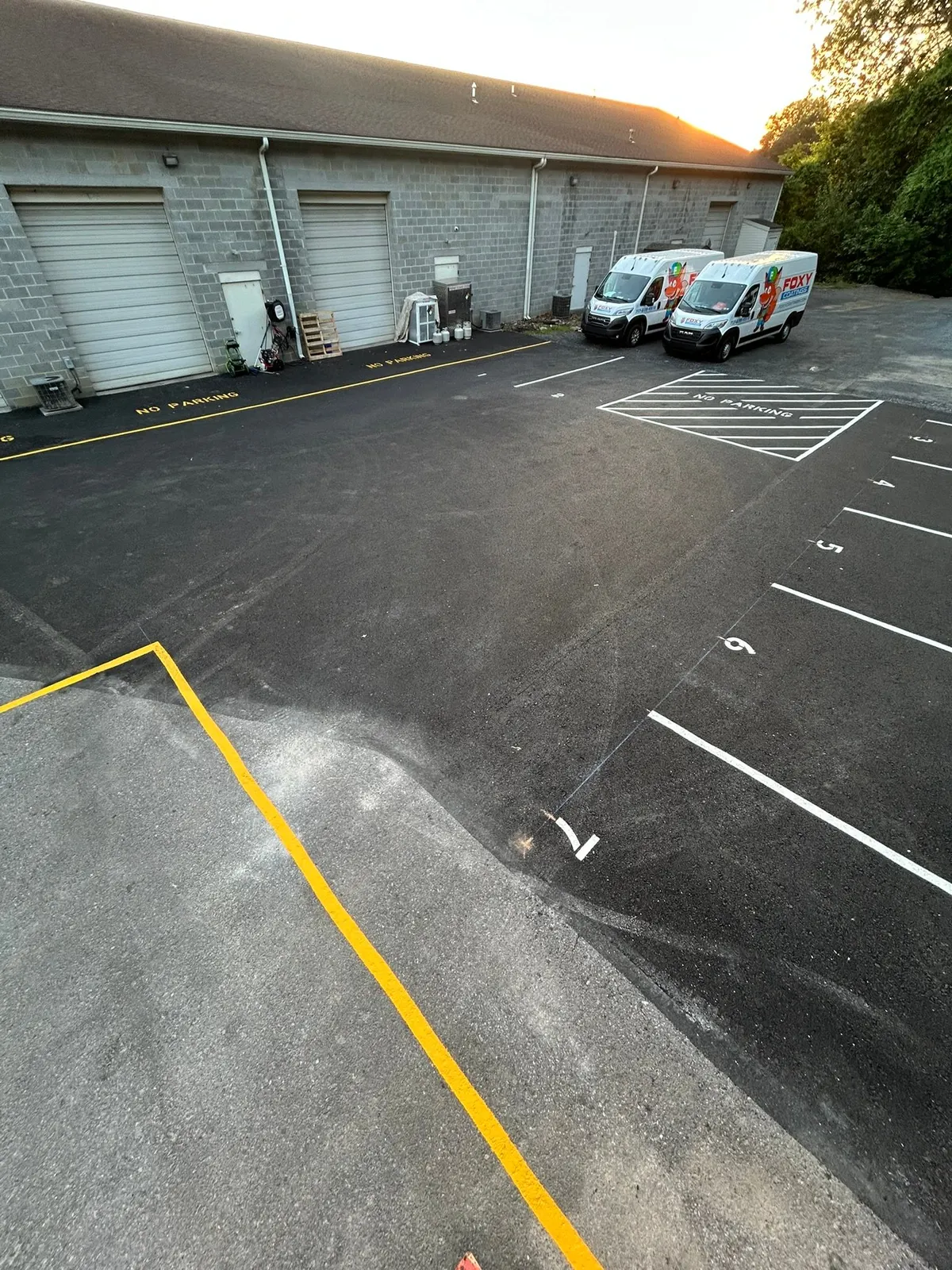 Numbered rear lot restriped with white lines and an ADA stall