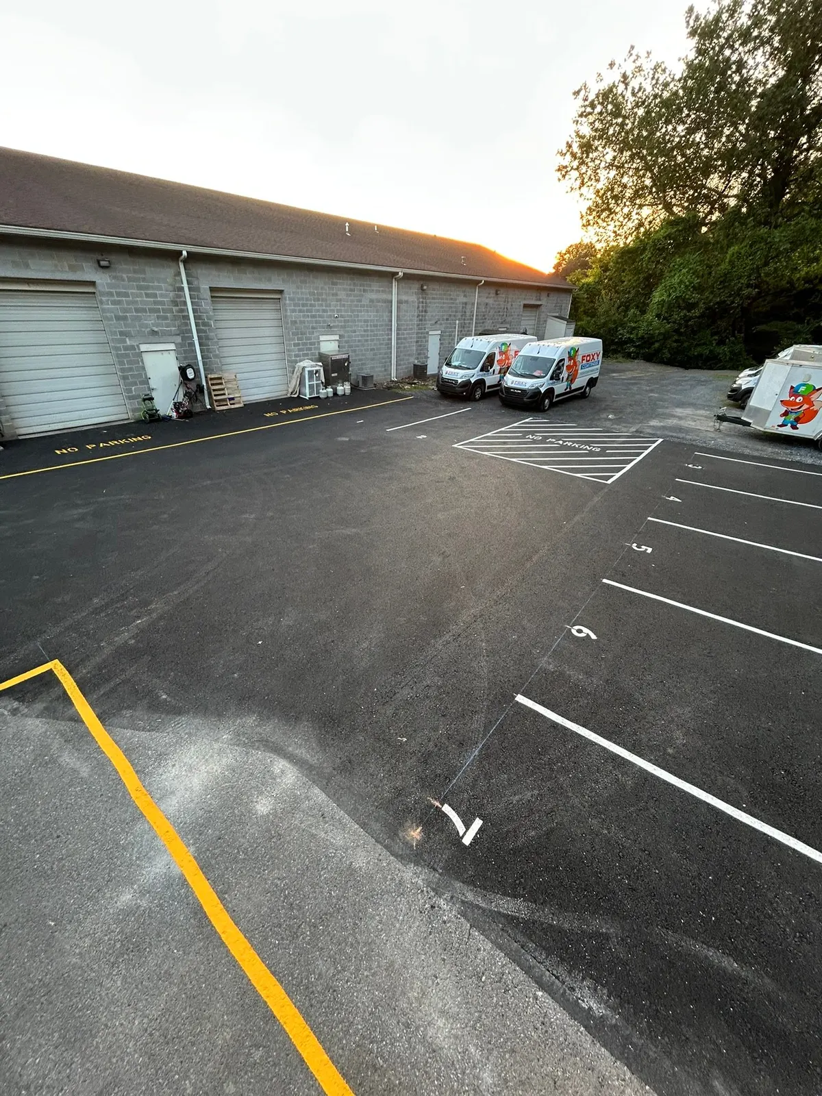 Rear lot with stall lines, stencils and a yellow curb line beside a building