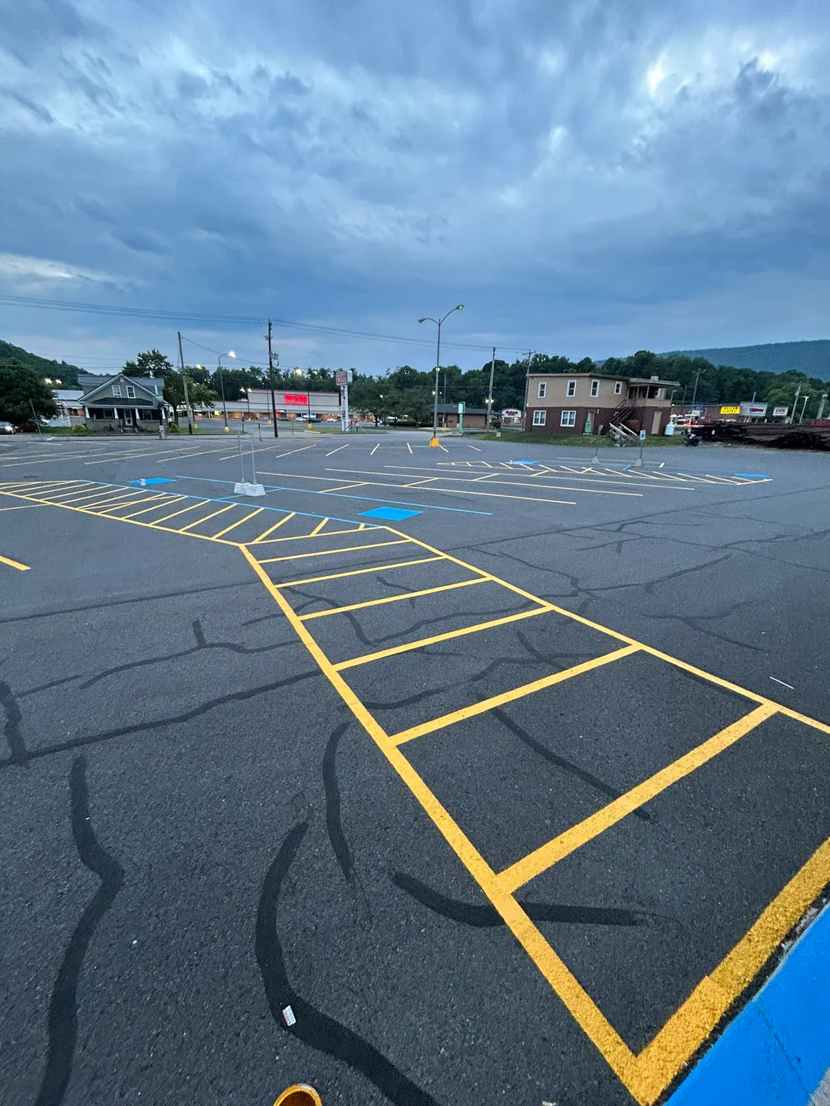 Angled yellow parking stripes laid out on a crack-filled asphalt lot