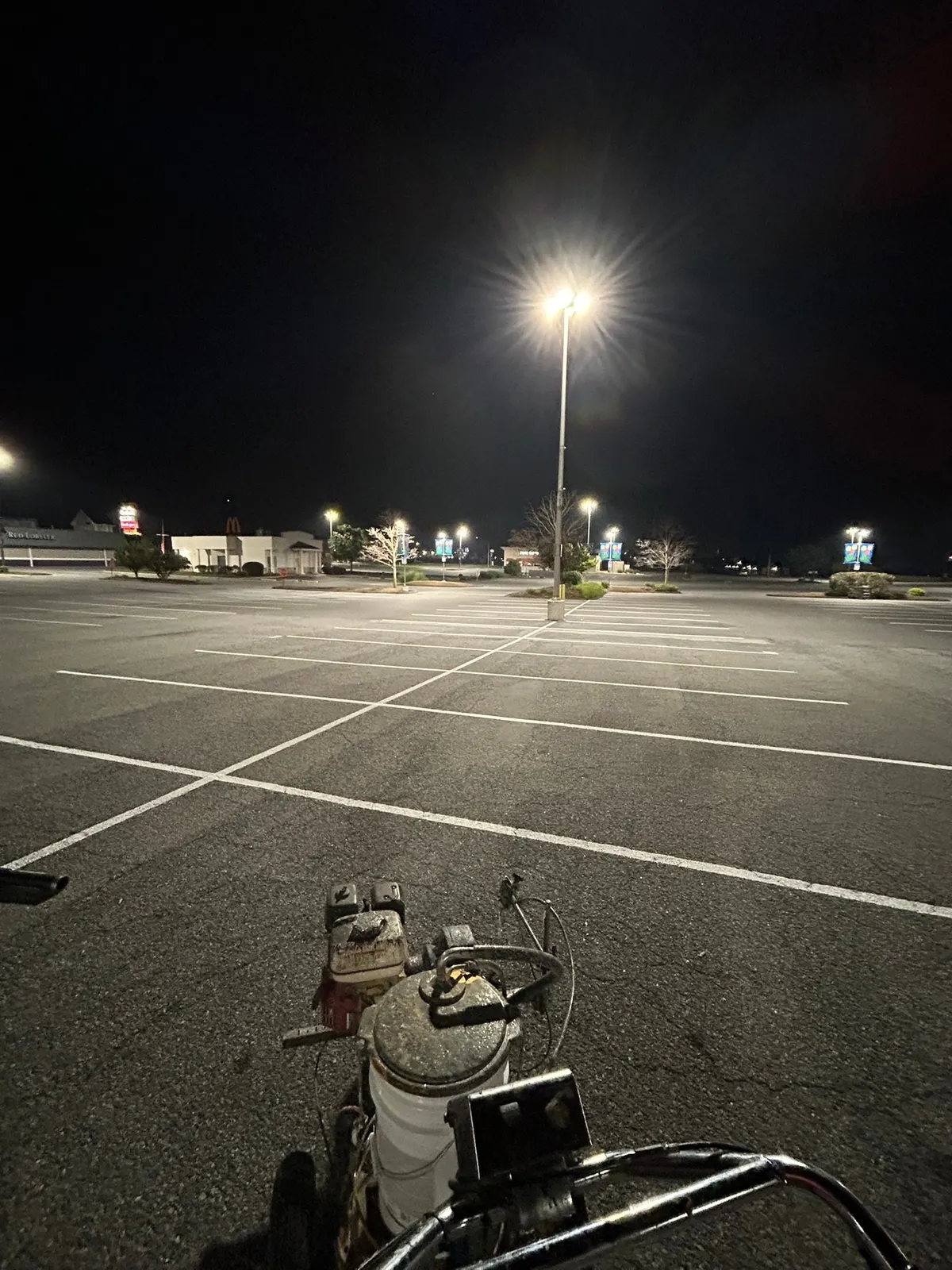 Line striping machine on a freshly marked commercial lot at night
