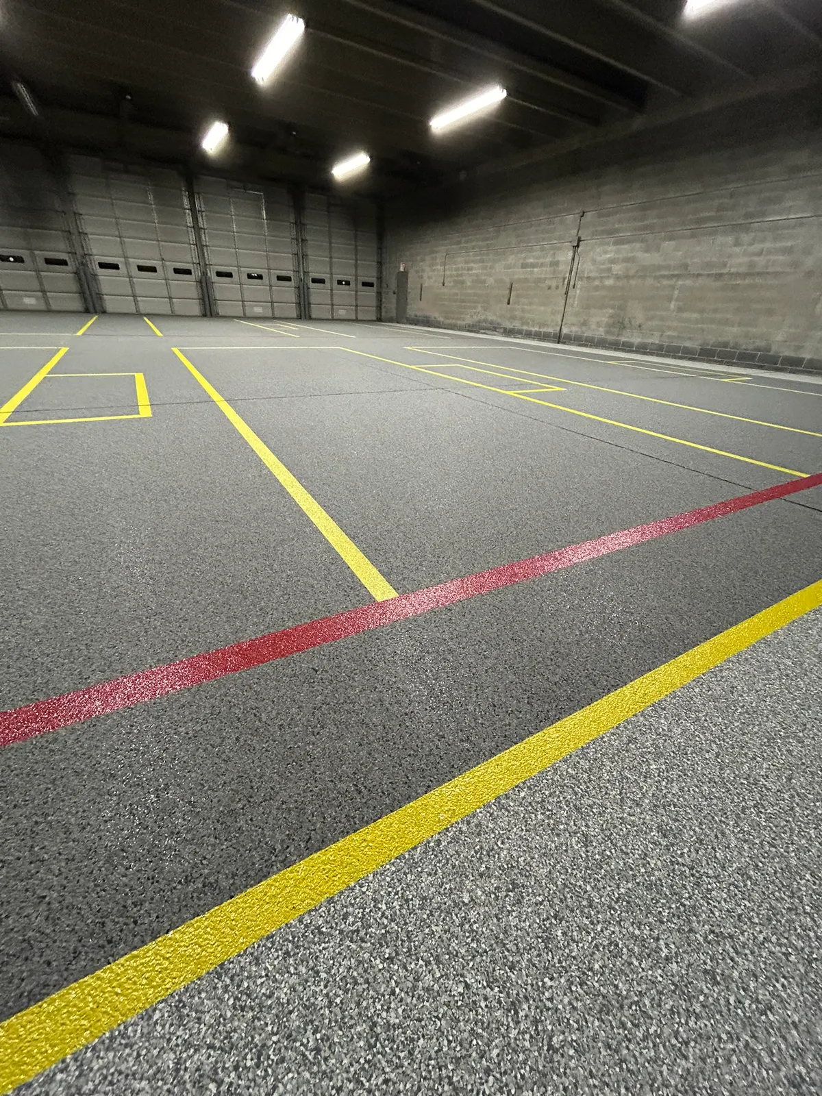 Close view of crisp red and yellow floor marking lines in a warehouse