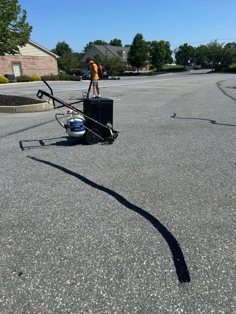 Professional crew using spray wand and squeegee to apply sealcoat to a commercial parking lot in Lancaster PA.