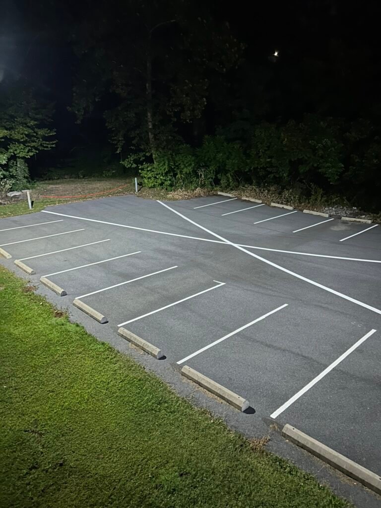 Comparison of faded parking lot lines versus freshly painted white striping on black sealcoated asphalt